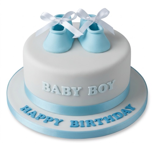 Round white cake with blue baby booties, 'BABY BOY' text, and 'HAPPY BIRTHDAY' on the board.