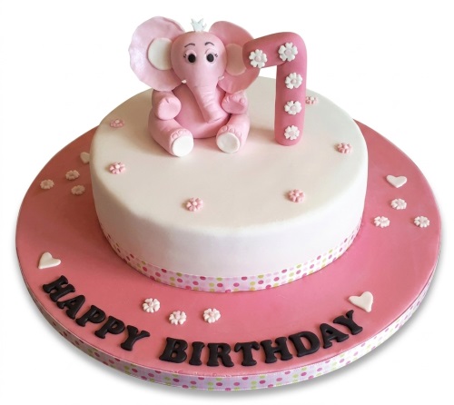 Round white and pink fondant cake with a pink elephant topper, a number 7 topper, and "Happy Birthday" written on the board.