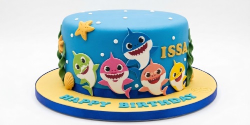 Round blue fondant cake decorated with Baby Shark characters, starfish, seashells, and seaweed.