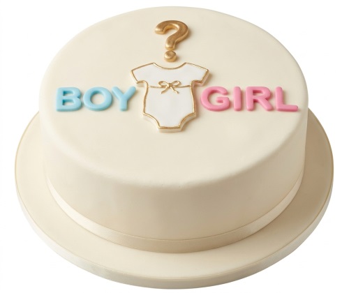 Round cream gender reveal Baby Shower cake with a gold question mark, white baby grow, blue "BOY" and pink "GIRL" lettering.