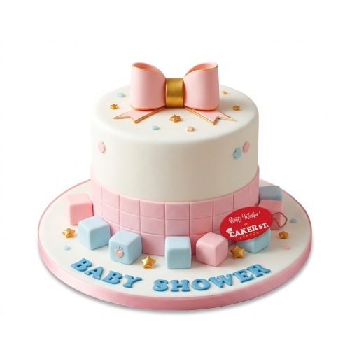 White baby shower cake with pink bow, gold stars, and pink and blue baby blocks.