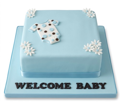 Two-tier blue baby shower cake with white and blue polka dot baby grow and white flowers.