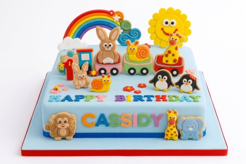Two-tiered light blue fondant cake decorated with cartoon animals, a rainbow, a train, and 'Happy Birthday' text.