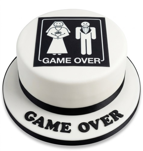 White round cake with black 'Game Over' text and bride and groom icons on top, with 'Game Over' spelled out on the cake board.