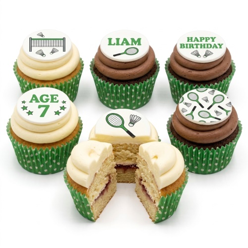 Six cupcakes with green polka dot cases and badminton-themed edible toppers. One cupcake is cut in half revealing jam filling.