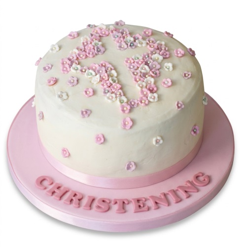 Round white christening cake with pink floral cross and 'CHRISTENING' text on board.