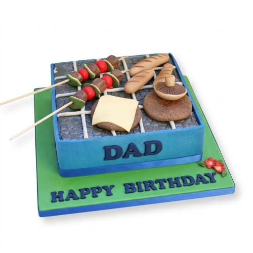 Novelty BBQ grill birthday cake with edible skewers, burger, mushrooms, and bread rolls.