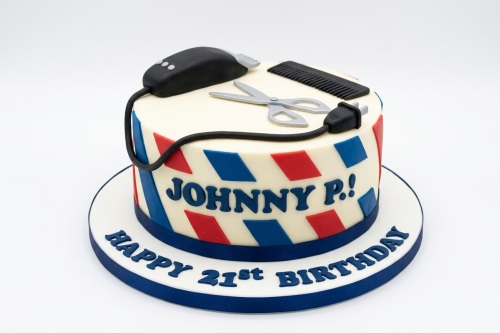 Barber theme birthday cake with edible hair clipper, comb, scissors, and red and blue stripes.