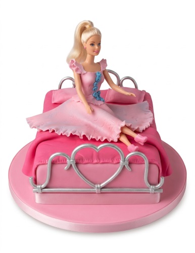 Pink Barbie doll birthday cake on a bed with silver heart details.