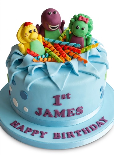 Light blue single-tier Barney and Friends birthday cake with purple, green, and yellow character toppers, colourful streamers, and custom age text.