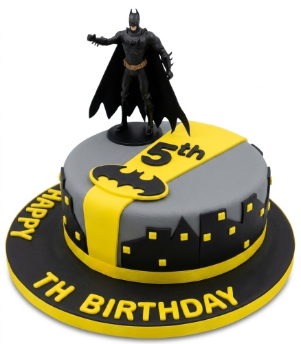 Batman themed birthday cake with a black and grey cityscape, yellow accents, and a Batman figurine topper.