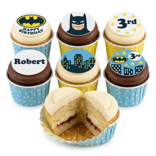 A set of Batman themed birthday cupcakes with yellow and blue wrappers, featuring Batman logo, Batman face, cityscape, and a custom age topper.