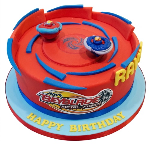 Round red Beyblade birthday cake with blue accents, two Beyblade tops, and a Beyblade Metal Fusion logo.