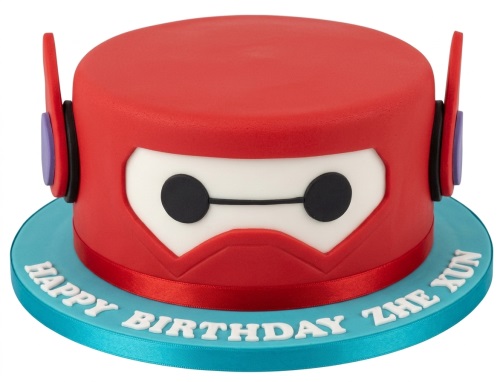 Round red Baymax character birthday cake with white face and black eyes on a blue board.