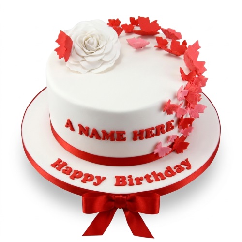 White single-tier birthday cake with red ribbon, white sugar rose, red and pink butterflies, and a personalised message.