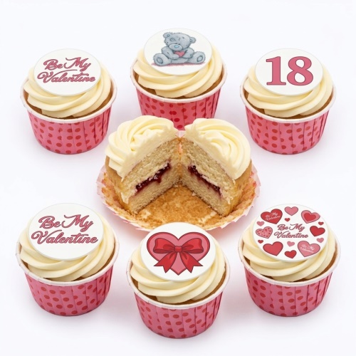 Valentines Day cupcakes with white icing, pink wrappers, heart, teddy bear, and 'Be My Valentine' toppers.