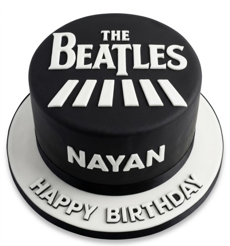 Round black and white cake with 'THE BEATLES' logo and Abbey Road stripes on top, with a custom name and 'HAPPY BIRTHDAY' message on the cake board.
