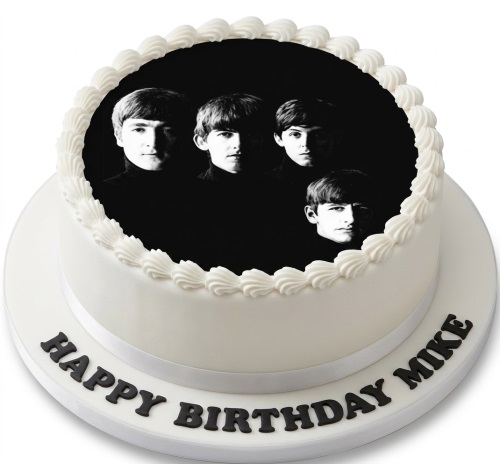 Round white birthday cake with a black and white edible photo of The Beatles on top, and black 'Happy Birthday' lettering.