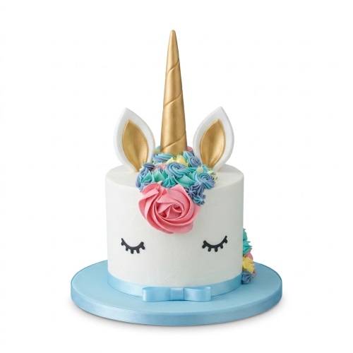 White unicorn cake with gold horn, ears, pastel flowers, and blue ribbon