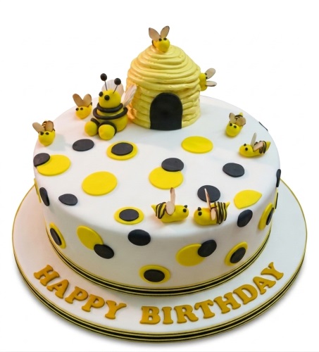 Round white birthday cake with yellow and black polka dots, 3D beehive and bee decorations.