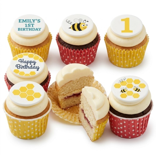A selection of bee theme birthday cupcakes with bee, honeycomb, and number one toppers, some in yellow and red polka dot wrappers.