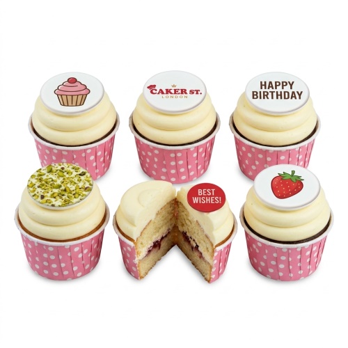 Assortment of cupcakes with white icing and various edible toppers in pink polka dot cases.