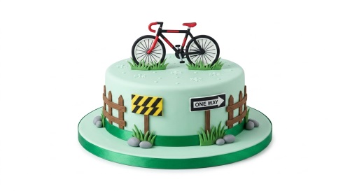 Mint green birthday cake with a red and black bicycle topper, fence, grass, and road signs.