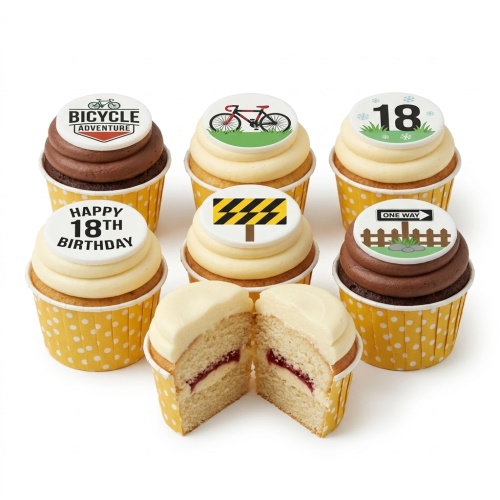 A selection of cupcakes with cycling and road sign themed edible toppers, including bicycles, a 'Bicycle Adventure' logo, 'One Way' sign, and a hazard sign.