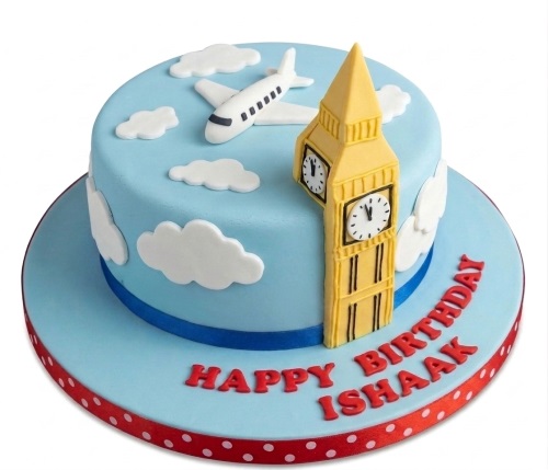 Round blue fondant cake with white clouds, an airplane, 3D yellow Big Ben, and red 'Happy Birthday' message.