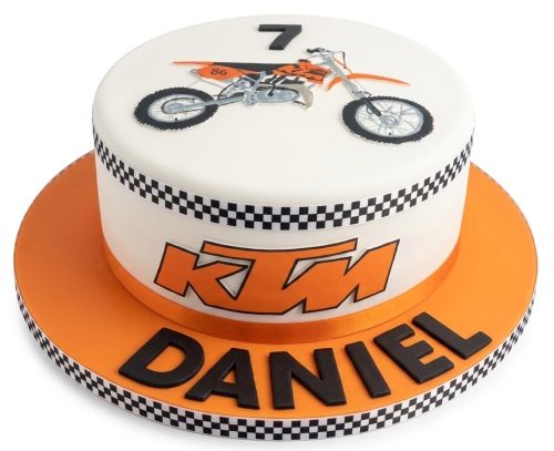 White round cake with orange KTM dirt bike design, black and white checkered ribbon, and custom age topper.