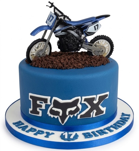 Blue fondant motocross birthday cake with a dirt bike topper and "FOX" logo.