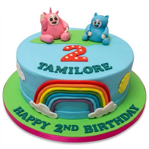 Round blue 2nd birthday cake with pink and blue friendly characters, a red number two, and a rainbow decoration.