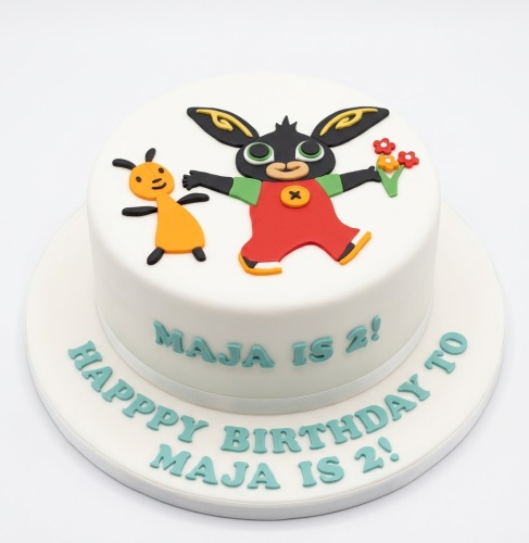 Round white fondant cake with edible Bing Bunny and Flop figures, decorated with colourful flowers.