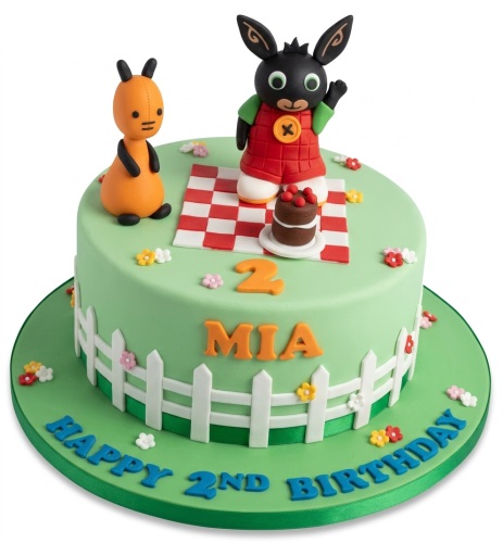 Round green Bing Bunny birthday cake with Bing and Flop figures, picnic scene, fence, and custom age.