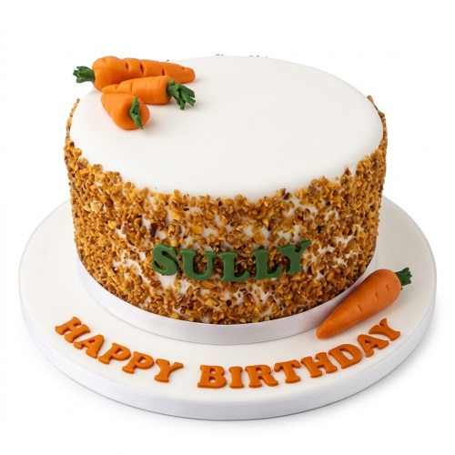 Round white birthday cake with fondant carrots, nut coating, and a personalised name.