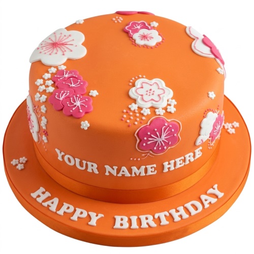 Orange birthday cake with pink and white floral decorations and space for a custom name.
