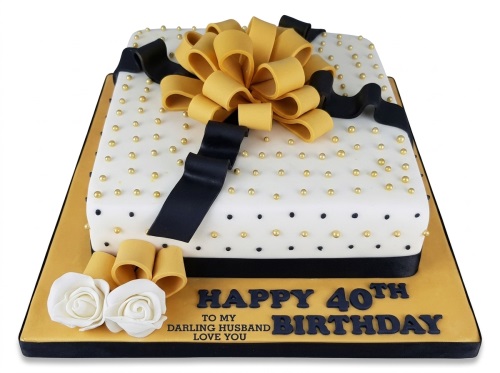 White, black, and gold gift box birthday cake with a large bow and sugar roses, featuring a custom age and message.