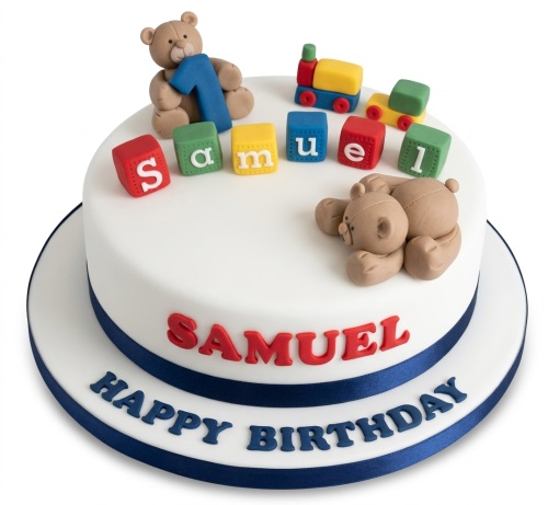 White 1st birthday cake with teddy bears, colourful building blocks, and a toy train.