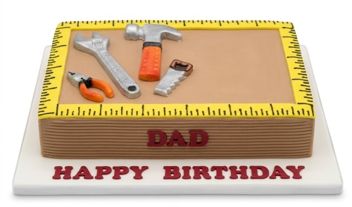 Rectangular tools theme birthday cake with edible wrench, hammer, pliers, and saw decorations, and a yellow measuring tape border.