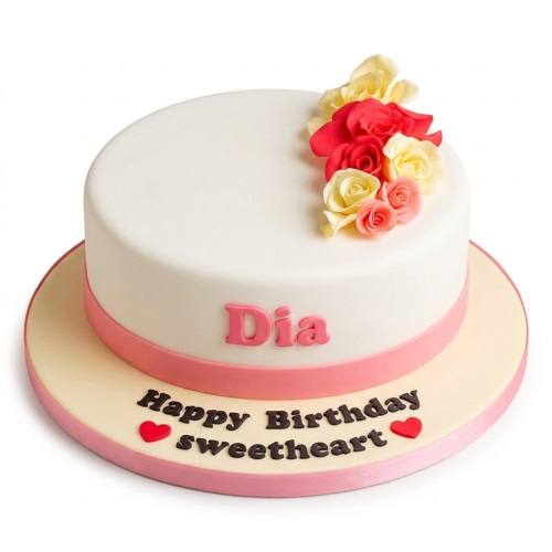 Elegant white round cake with red, yellow, and pink sugar flowers and a pink ribbon.