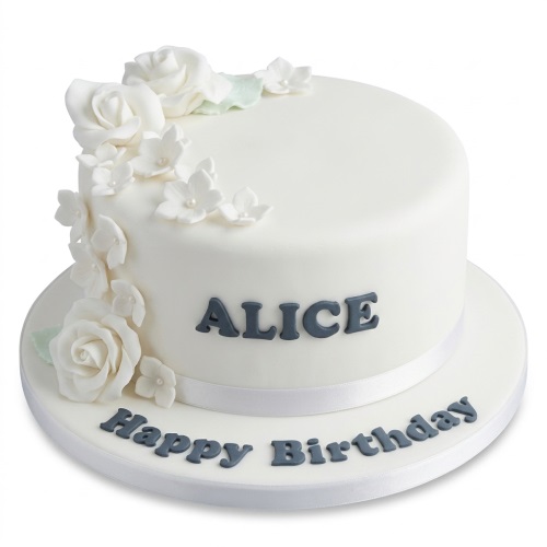 White round birthday cake with white sugar roses, small flowers, green leaves, and a white ribbon.