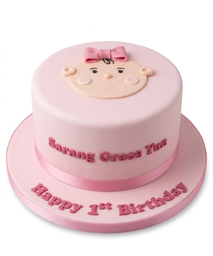 Pink baby girl 1st birthday cake with baby face decoration and personalised name