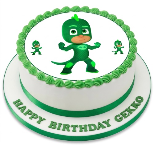 Round white birthday cake with a large edible image of the green PJ Masks character Gekko, with green piped frosting and a green ribbon.