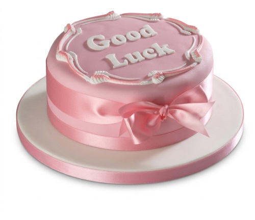 Round pink good luck cake with white "Good Luck" message and pink satin ribbon.