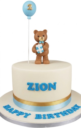 Round cream cake with a teddy bear topper, blue balloon with custom age, and personalised name.