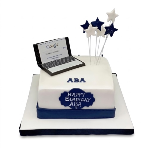 White square birthday cake with a laptop topper showing Google and blue star decorations.