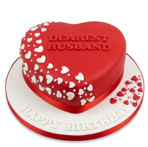 Red heart-shaped birthday cake with white hearts and 'Dearest Husband' message.