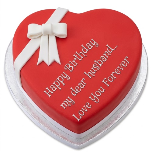 Red heart-shaped birthday cake with white ribbon and bow, featuring a personalised message.