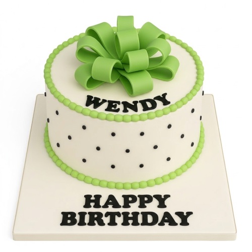 Round white birthday cake with black polka dots, green bow, and green beaded borders.