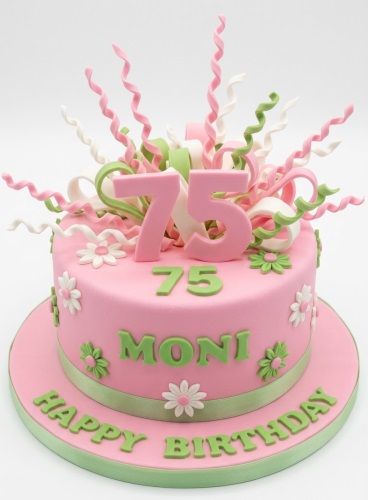 Pink and green round birthday cake with white and green daisy flowers, curly sugarpaste swirls, and a custom age topper.